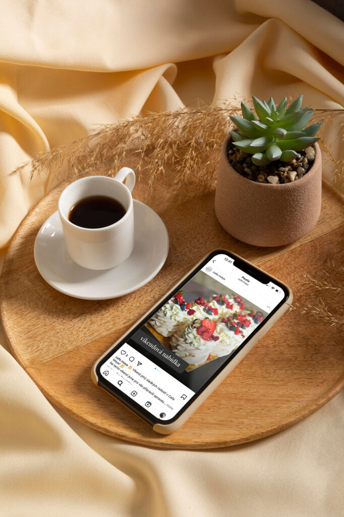 smartphone na stolku se &scaron;&aacute;lkem k&aacute;vy a rostlinou